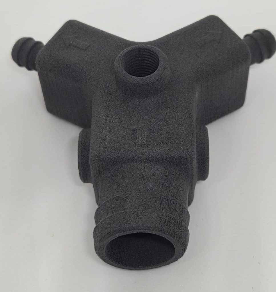Dark gray three-way hose fitting with barbed ends and a threaded central port, used for connecting irrigation hoses.